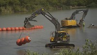 Para pekerja terus mengerahkan pelampung besar untuk digunakan sebagai penghalang perbatasan di sepanjang tepi sungai Rio Grande di Eagle Pass, Texas, Rabu (12/7/2023).  