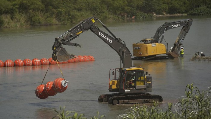 Texas Pasang Penghalang Apung di Sungai untuk Cegah Migran Menyebrang Workers continue to deploy large buoys to be used as a border barrier along the banks of the Rio Grande in Eagle Pass, Texas, Wednesday, July 12, 2023. The floating barrier is being deployed in an effort to block migrants from entering Texas from Mexico. (AP Photo/Eric Gay)