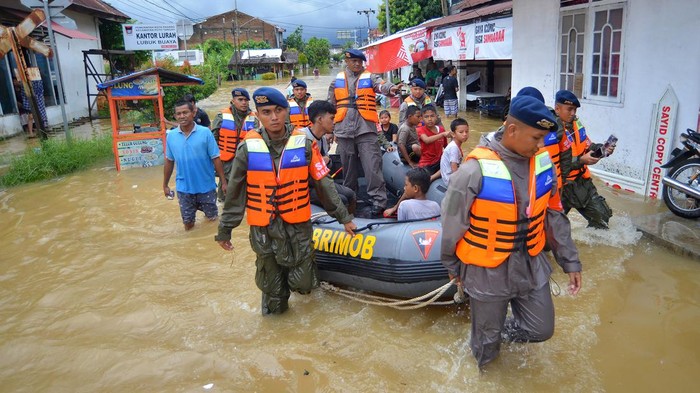 Personel Brimob membagikan makanan ringan kepada sejumlah warga di Lubuk Buaya Padang, Sumatera Barat, Jumat (14/7/2023). Akibat intensitas tinggi sejak Kamis (13/7/2023) malam membuat air sungai di kota itu meluap dan mengakibatkan banjir di sejumlah kecamatan.  ANTARA FOTO/Iggoy el Fitra/hp.