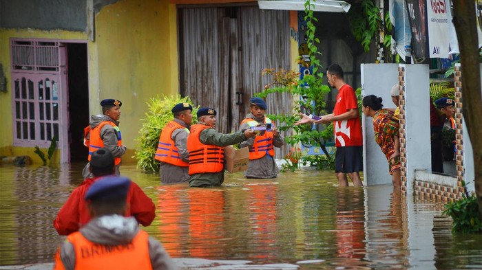 Personel Brimob membagikan makanan ringan kepada sejumlah warga di Lubuk Buaya Padang, Sumatera Barat, Jumat (14/7/2023). Akibat intensitas tinggi sejak Kamis (13/7/2023) malam membuat air sungai di kota itu meluap dan mengakibatkan banjir di sejumlah kecamatan.  ANTARA FOTO/Iggoy el Fitra/hp.