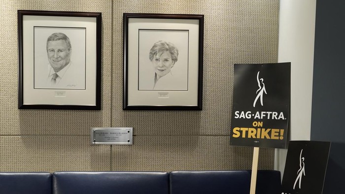 Portraits of SAG-AFTRA founding co-presidents Ken Howard and Roberta Reardon hang next to strike signage following a press conference announcing a strike by The Screen Actors Guild-American Federation of Television and Radio Artists on Thursday, July, 13, 2023, in Los Angeles. This marks the first time since 1960 that actors and writers will picket film and television productions at the same time. (AP Photo/Chris Pizzello)