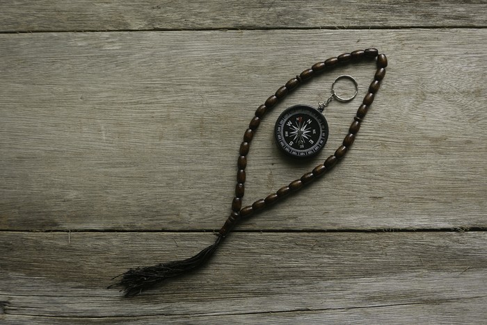 prayer beads beads and compass on wooden background.