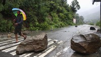 Bongkahan batu besar dari longsoran menutupi jalan raya. AP/Aqil Khan.