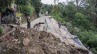 Seorang montir motor berdiri di luar tokonya melihat jalan, yang sebagian besar longsor akibat hujan deras di Dharamshala, Himachal Pradesh, India, Senin (10/7/2023). AP/Ashwini Bhatia.