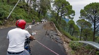 Jalan yang longsor tidak bisa dilintasi. Akibatnya, pengguna jalan harus bergantian menggunakan sisi yang masih bisa dilintasi. AP/Ashwini Bhatia.