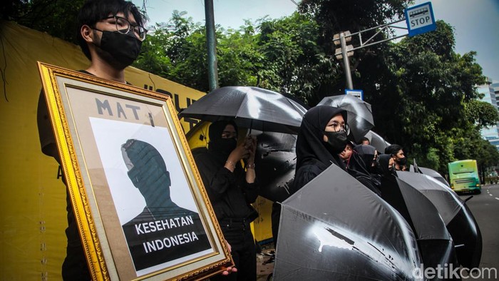 Massa Berpayung Tolak UU Kesehatan di Kantor Kemenkes Massa menggelar aksi damai menolak UU Kesehatan yang baru disahkan. Sambil membawa payung, massa aksi di seberang kantor Kemenkes, Jakarta.