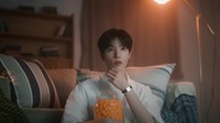 Trainee dari Korea bernama Minjae tampil dalam busana putih memeluk sekaleng cemilan sambil nonton film horor. (Foto: dok. SM Entertainment)  