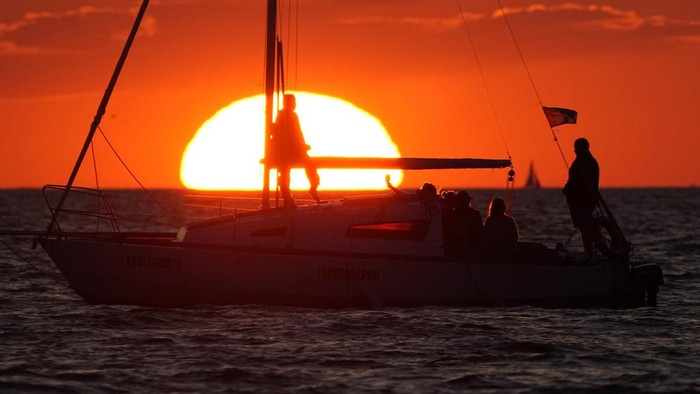 A woman plays with her dog at a beach on the Finnish Gulf as the sun sets, in St. Petersburg, Russia, Thursday, July 13, 2023. (AP Photo/Dmitri Lovetsky)