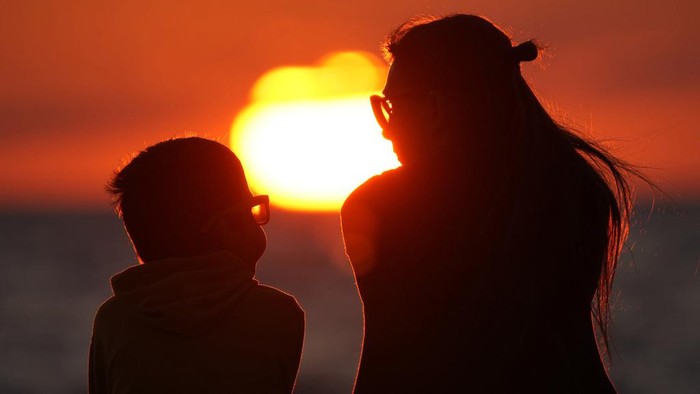 Russia Daily Life A woman plays with her dog at a beach on the Finnish Gulf as the sun sets, in St. Petersburg, Russia, Thursday, July 13, 2023. (AP Photo/Dmitri Lovetsky)