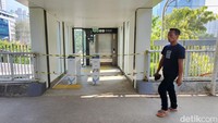 Warga melintas di halte yang tidak jadi beroperasi hari ini.