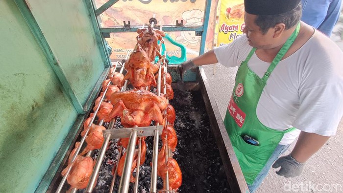 Narsim (44) memanggang ayam guling madu yang dijajakan di depan Pasar Cilongok, Banyumas, Jumat (14/7/2023) petang.