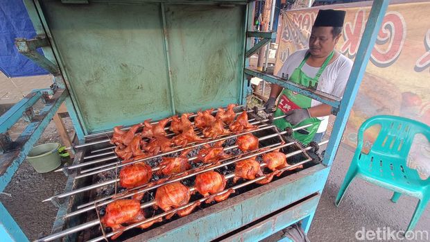 Narsim (44) memanggang ayam guling madu yang dijajakan di depan Pasar Cilongok, Banyumas, Jumat (14/7/2023) petang.