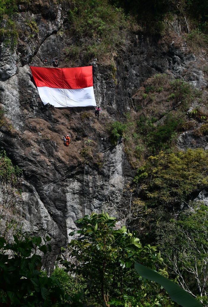 Sang Merah Putih Berkibar di Tebing Lereng Wilis Pegiat panjat tebing membuat jalur pengibaran bendera merah putih di sebuah tebing kawasan lereng Gunung Wilis, Kabupaten Madiun, Jawa Timur, Sabtu (15/7/2023). Jalur tersebut akan digunakan untuk pengibaran Bendera Merah Putih oleh pegiat panjat tebing bersama prajurit TNI pada peringatan HUT ke-78 Proklamasi Kemerdekaan RI 17 Agustus mendatang. ANTARA FOTO/Siswowidodo/nym.
