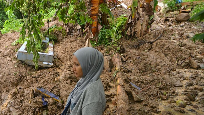TPU di Padang Dihantam Longsor, Sejumlah Mayat Keluar dari Kuburan Warga melintas di depan kuburan yang terbongkar akibat longsor di Seberang Padang, Kota Padang, Sumatera Barat, Jumat (14/7/2023). Areal perkuburan di tepi bukit Seberang Padang itu longsor akibat intensitas hujan tinggi sejak Kamis (13/7/23) yang menyebabkan sejumlah makam terbongkar dan belasan jenazah keluar sehingga harus dikuburkan kembali. ANTARA FOTO/Iggoy el Fitra/tom.