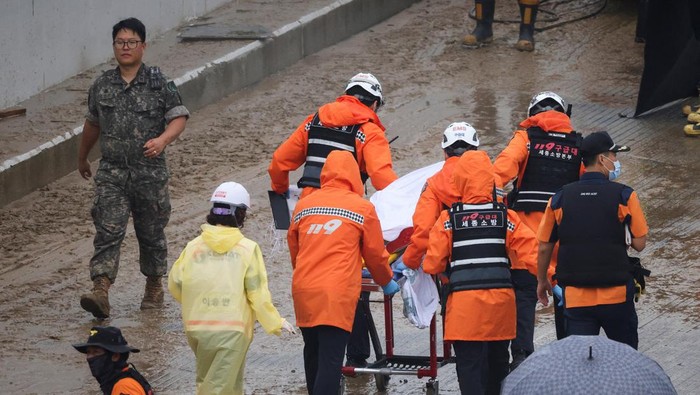 Rescue workers carry the body of a victim recovered during a search and rescue operation near an underpass that has been submerged by a flooded river caused by torrential rain in Cheongju, South Korea, July 16, 2023.   REUTERS/Kim Hong-ji