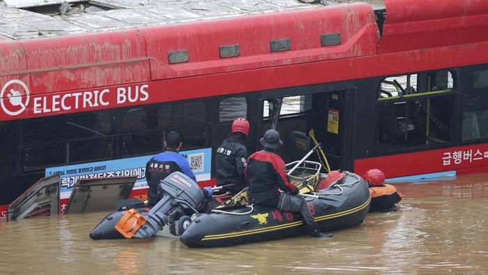 Rescuers conduct a search operation along a road submerged by floodwaters leading to an underground tunnel in Cheongju, South Korea, Sunday, July 16, 2023. Days of heavy rain triggered flash floods and landslides and destroyed homes, leaving scores of people dead and forcing thousands to evacuate, officials said Sunday. (Kim Ju-hyung/Yonhap via AP)