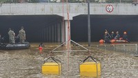 Tim penyelamat mencari korban di sepanjang jalan yang tergenang air banjir menuju terowongan bawah tanah di Cheongju, Korea Selatan, Minggu (16/7/2023). Hujan deras berhari-hari memicu banjir bandang dan tanah longsor. South Korea National Fire Agency/AP Photo
