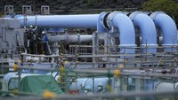 Orang-orang bekerja dengan pipa biru untuk mengangkut air laut, bagian dari fasilitas pelepasan air radioaktif yang diolah ke laut dari pembangkit listrik tenaga nuklir Fukushima Daiichi di kota Futaba, timur laut Jepang, Jumat (14/7/2023). 