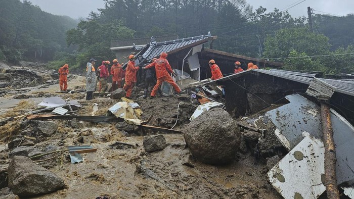 In this photo provided by the South Korea National Fire Agency, rescue workers search for people in a house collapsed after a landslide caused by heavy rain in Yeongju, South Korea, Saturday, July 15, 2023. Days of heavy rain in South Korea have left over 20 people dead and others missing in landslides, floods and other incidents. (South Korea National Fire Agency, via AP)