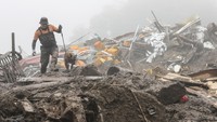 Seorang petugas penyelamat dengan seekor anjing mencari orang-orang di lokasi tanah longsor yang disebabkan oleh hujan lebat di Yecheon, Korea Selatan, Minggu (16/7/2023). Korsel sedang berada di musim panas dan telah terjadi hujan lebat selama 4 hari terakhir, menyebabkan bendungan besar meluap. AP/Yun Kwan-shick