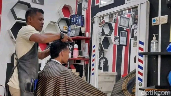 Hanz, salah satu tukang cukur rambut di Pasuruan yang cuan saat tahun ajaran baru.