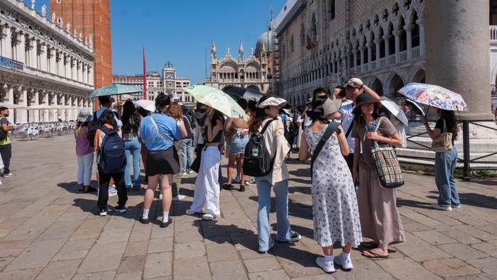Tourists shelter from the sun in St. Mark's Square as the city gears up for 'Redentore' festival celebrations in Venice, Italy, July 15, 2023. REUTERS/Manuel Silvestri