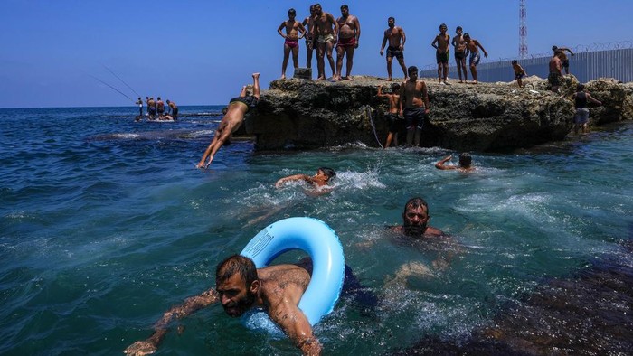 Lebanon Gerah Banget, Warga Ramai-ramai Nyemplung ke Laut People jump in the water to cool off on a sweltering hot day in the Mediterranean Sea in Beirut, Lebanon, Sunday, July 16, 2023. Were forecast to reach as high as 40 degrees Celsius, 104 Fahrenheit, in some parts of Lebanon. (AP Photo/Hassan Ammar)