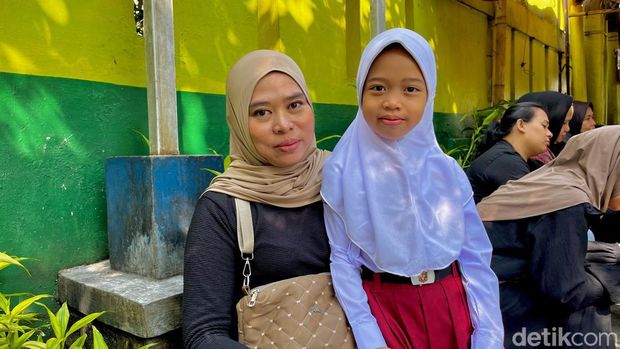 Orang tua murid dan putrinya hari pertama masuk sekolah.