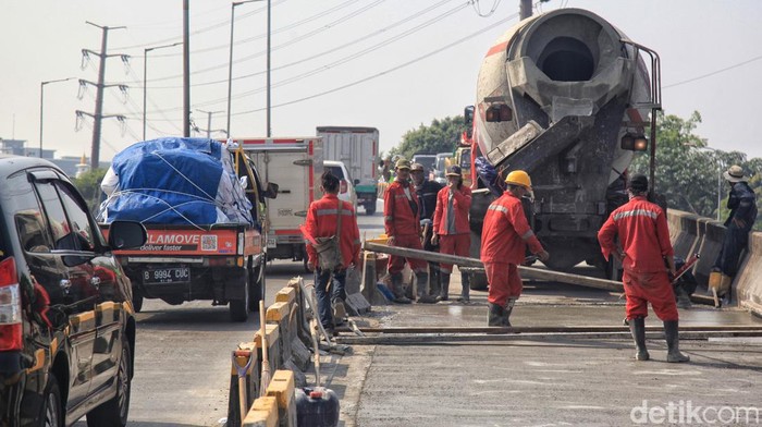 Pembetonan Jalan di Hari Senin Bikin Daan Mogot Makin Kusut Petugas kepolisian mengatur arus lalu-lintas di pintu masuk fly over Pesing, Jl Daan Mogot, Jakarta, Senin (17/7/2023).