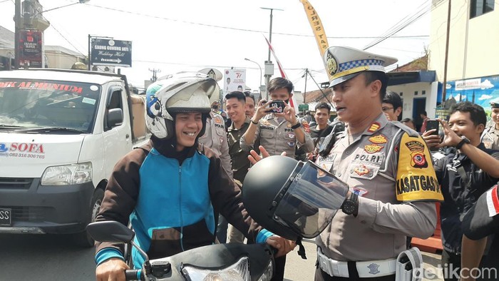Polisi memberikan helm untuk pemotor.