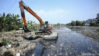 Alat berat beraktivitas di aliran kali yang penuh sampah di Desa Sumber Jaya, Tambun Selatan, Bekasi, Senin (17/7/2023).  