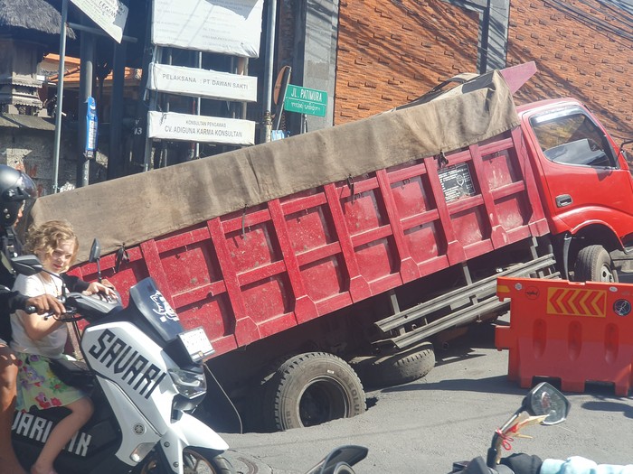 Sebuah truk aspal yang membawa 12 ton aspal jeblos ke dalam jalan di sekitar Jalan Majapahit, Kuta, Badung, Senin (17/7/2023). (Ronatal Siahaan/detikBali).