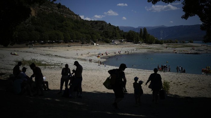 A kayaker waves to tourists preparing to packraft along the Verdon Gorge in southern France, Monday, June 19, 2023. Human-caused climate change is lengthening droughts in southern France, meaning the reservoirs are increasingly drained to lower levels to maintain the power generation and water supply needed for nearby towns and cities. It's concerning those in the tourism industry, who are working out how to keep their lakeside businesses afloat. (AP Photo/Daniel Cole)