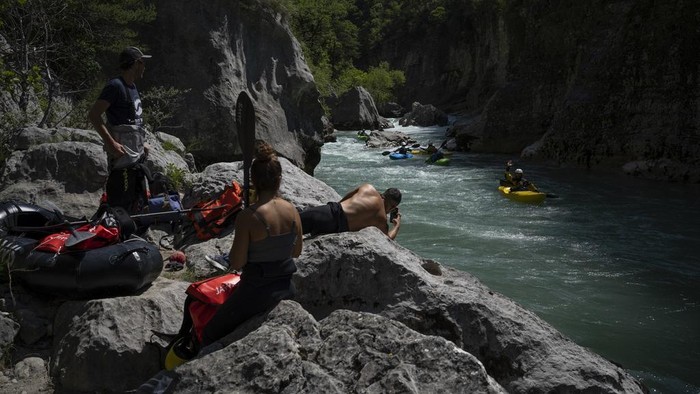 Wisata Air di Ngarai Prancis Terancam Kekeringan A kayaker waves to tourists preparing to packraft along the Verdon Gorge in southern France, Monday, June 19, 2023. Human-caused climate change is lengthening droughts in southern France, meaning the reservoirs are increasingly drained to lower levels to maintain the power generation and water supply needed for nearby towns and cities. It's concerning those in the tourism industry, who are working out how to keep their lakeside businesses afloat. (AP Photo/Daniel Cole)