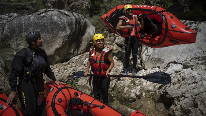 A kayaker waves to tourists preparing to packraft along the Verdon Gorge in southern France, Monday, June 19, 2023. Human-caused climate change is lengthening droughts in southern France, meaning the reservoirs are increasingly drained to lower levels to maintain the power generation and water supply needed for nearby towns and cities. It's concerning those in the tourism industry, who are working out how to keep their lakeside businesses afloat. (AP Photo/Daniel Cole)