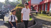 Farel Prayoga berjalan bersama salah seorang gurunya. Manajemen memastikan bahwa Farel memang punya mimpi sekolah di SMPN 1 Cluring yang dikenal punya banyak murid berprestasi. (Foto: Eka Rima/detikJatim)