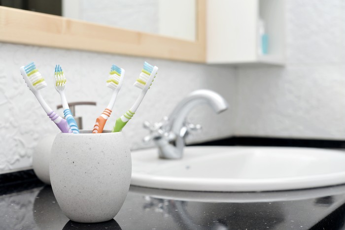Toothbrushes in glass with a soap dispenser   in a bathroom closeup
