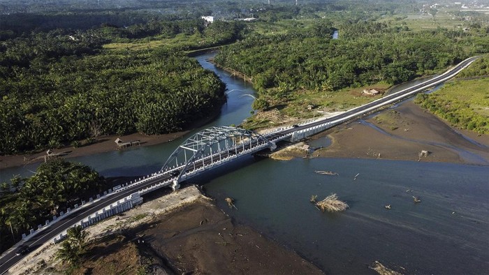 Foto udara kendaraan melintasi Jembatan Wiradinata Rangga Jipang di Kabupaten Pangandaran, Jawa Barat, Senin (17/7/2023). Pemerintah Povinsi Jawa Barat telah memperbaiki dan membangun jalan baru atau jalan lintas pantai sepanjang 1.150 kilometer yang menghubungkan Pantai Pangandaran dengan Pantai Madasari, untuk menunjang sektor pariwisata. ANTARA FOTO/Adeng Bustomi/rwa.