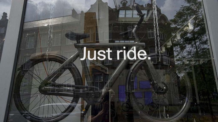 A man parked his VanMoof bicycle outside the VanMoof head office to take a picture in Amsterdam, Netherlands, Tuesday, July 18, 2023. Dutch electric bicycle maker VanMoof has been declared bankrupt, slamming the brakes on a company that won design awards for its pared-back electric bikes but struggled to meet soaring demand and fix glitches. (AP Photo/Peter Dejong)