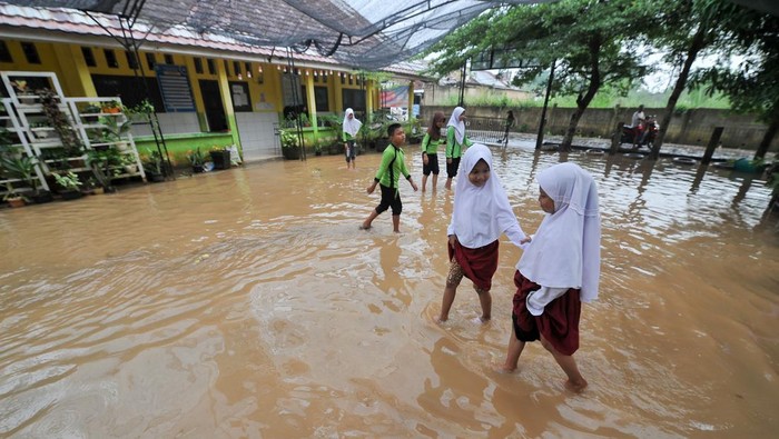 Pelajar dan guru membersihkan kelas yang terendam banjir di SDN 98 Kota Jambi, Jambi, Selasa (18/7/2023). Banjir yang terjadi akibat meluapnya anak sungai di belakang sekolah setelah kota itu dilanda hujan deras selama 3 jam lebih mengakibatkan hampir semua ruangan kelas terendam,  dan selama tahun ini sekolah tersebut telah terdampak banjir hingga sepuluh kali. ANTARA FOTO/Wahdi Septiawan/aww.