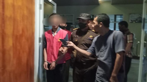 Salah satu tersangka korupsi pengadaan alat metrologi Disperindag Dompu mengenakan baju merah dan tangan diborgol.