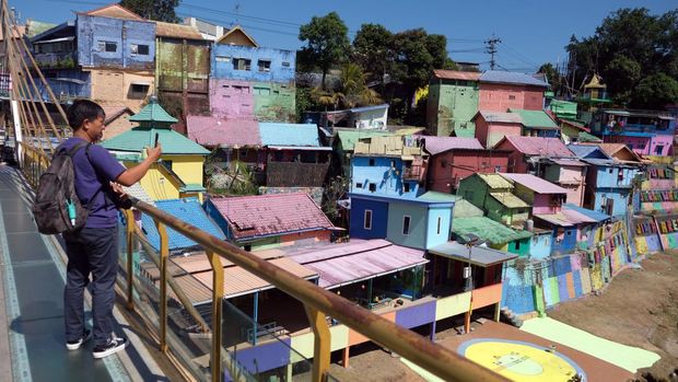 Wisatawan berjalan di jembatan kaca saat mengunjungi Kampung Warna-Warni Jodipan di Malang, Jawa Timur, Kamis (20/7/2023). Kampung warna-warni yang dibuka sebagai objek wisata sejak tahun 2016 tersebut saat ini dicat ulang secara bertahap pada ratusan rumah milik warga setempat yang dimulai dari awal tahun 2023 untuk meningkatkan jumlah kunjungan wisata. ANTARA FOTO/Nyoman Hendra Wibowo/rwa.