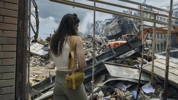 Seorang wanita menyaksikan personel layanan darurat bekerja di lokasi bangunan yang hancur setelah serangan Rusia di Odesa, Ukraina, Kamis, 20 Juli 2023. Rusia menggempur kota-kota selatan Ukraina, termasuk kota pelabuhan Odesa, dengan drone dan rudal selama beberapa menit. malam ketiga berturut-turut dalam gelombang pemogokan yang telah menghancurkan beberapa infrastruktur ekspor biji-bijian penting negara itu. (AP Photo/Libkos)