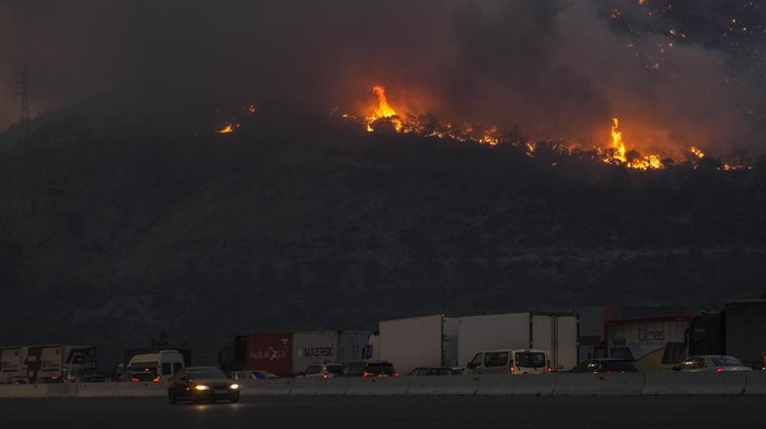 A firefighting helicopter dumps water in Mandra west of Athens, on Tuesday, July 18, 2023. In Greece, where a second heatwave is expected to hit Thursday, three large wildfires burned outside Athens for a second day. Thousands of people evacuated from coastal areas south of the capital returned to their homes Tuesday when a fire finally receded after they spent the night on beaches, hotels and public facilities. (AP Photo/Petros Giannakouris)