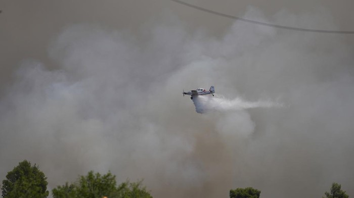A firefighter aircraft drops water onto a fire in Pournari village near Athens, on Tuesday, July 18, 2023. In Greece, where a second heatwave is expected to hit Thursday, three large wildfires burned outside Athens for a second day. Thousands of people evacuated from coastal areas south of the capital returned to their homes Tuesday when fire finally receded after they spent the night on beaches, hotels and public facilities. (AP Photo/Thanassis Stavrakis)