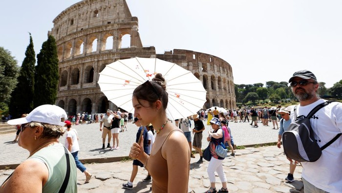 People walk near the Colosseum during a heat wave across Italy as temperatures are expected to rise further in the coming days, in Rome, Italy July 17, 2023. REUTERS/Remo Casilli