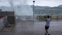 Seseorang melihat ombak di kawasan pejalan kaki selama topan di Hong Kong. Topan telah menyapo kota dan mulai mendekat ke China. AP/Louise Delmotte