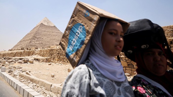 Tourists eat ice-creams amid a heatwave in front of the Great Pyramids of Giza, on the outskirts of Cairo, Egypt, July 19, 2023. REUTERS/Mohamed Abd El Ghany