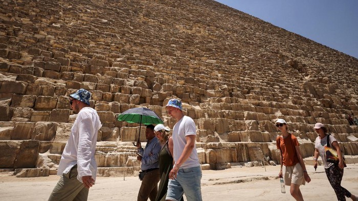 Tourists eat ice-creams amid a heatwave in front of the Great Pyramids of Giza, on the outskirts of Cairo, Egypt, July 19, 2023. REUTERS/Mohamed Abd El Ghany
