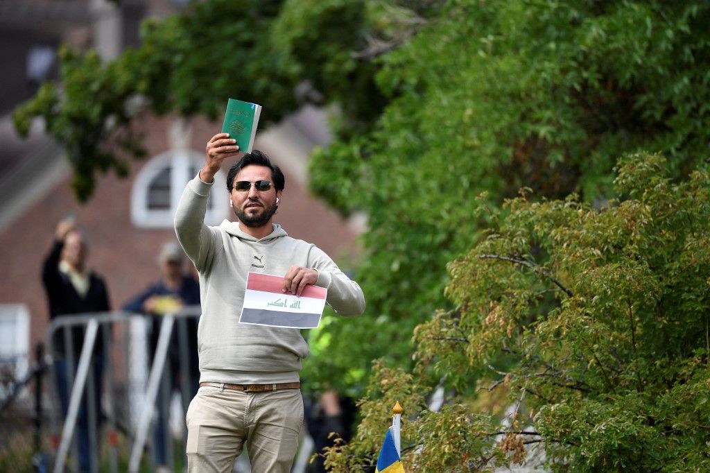 Protestor Salwan Momika holds up the Muslim holy book and a sheet of paper showing the flag of Iraq during a protest outside the Iraqi Embassy in Stockholm, Sweden, on July 20, 2023. Iraq warned Sweden on July 20, 2023 that it would cut diplomatic relations if a Koran-burning protest is allowed to go ahead in Stockholm, after protesters stormed and torched the Swedish embassy in Baghdad overnight. (Photo by Oscar Olsson / TT News Agency / AFP) / Sweden OUT